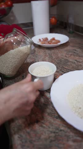 Elderly hands pouring raw white rice from a glass jar into a cup to measure it for cooking