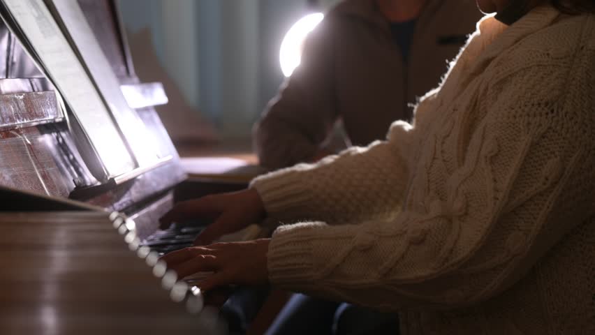 A woman playing the piano, her hands close-up on the keys. Black and white keys of a musical instrument.