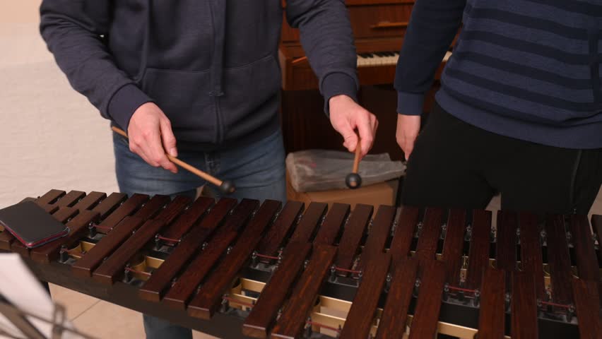 A man and a boy plays the xylophone, close-up of her hand and hits the keys with sticks. teacher and pupil in music school