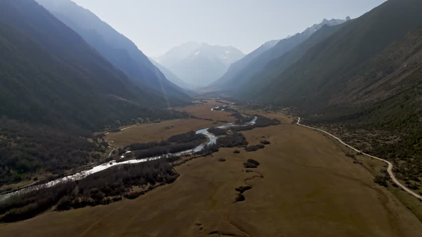 Aerial panoramic view of a mountain landscape with snow-capped peaks and autumn scenery