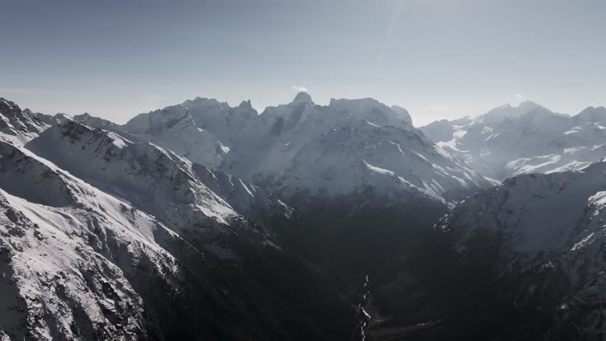 Aerial panoramic view of a mountain landscape with snow-capped peaks and autumn scenery