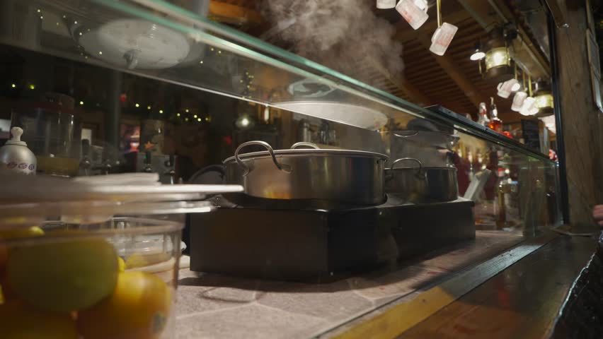 Buying hot mulled wine at the famous Muenchen Christkindlmarkt on Kaufingerstrasse. The illuminated wooden booth serves traditional Gluehwein to visitors during the festive Advent season in Germany