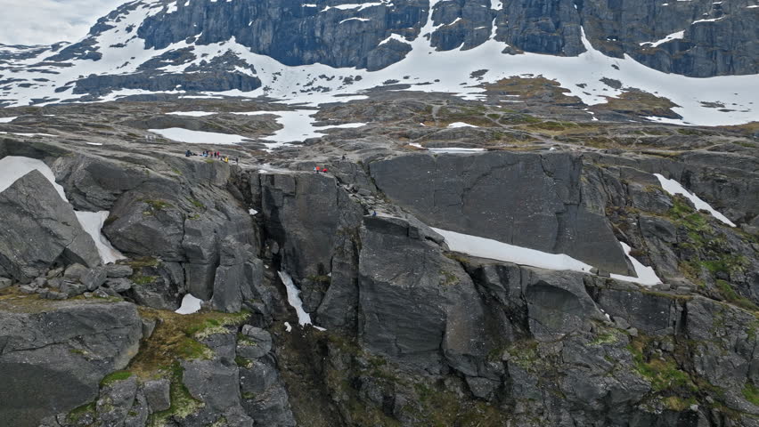 Rocky cliff formations near Trolltunga hiking area in Norway. Snow patches and sharp edges show rugged alpine terrain in early summer.