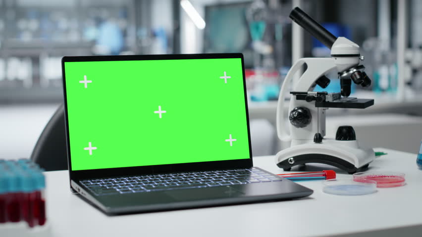 Isolated screen laptop on lab workbench next to microscope and liquid samples. Chroma key notebook on research station prepared for analyzing experimental data from chemical solution tests