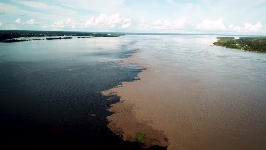 meeting of waters with a boat crossing the two rivers, Solimoes and Rio Negro in amazon brazil. High quality 4k footage