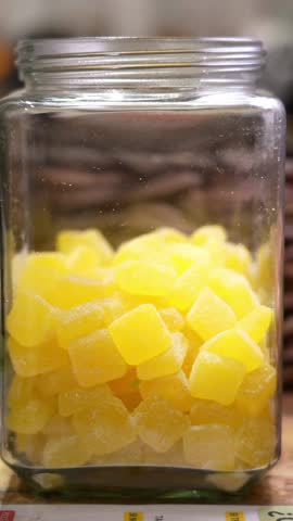 taking yellow gummy candies from a glass jar with tweezers