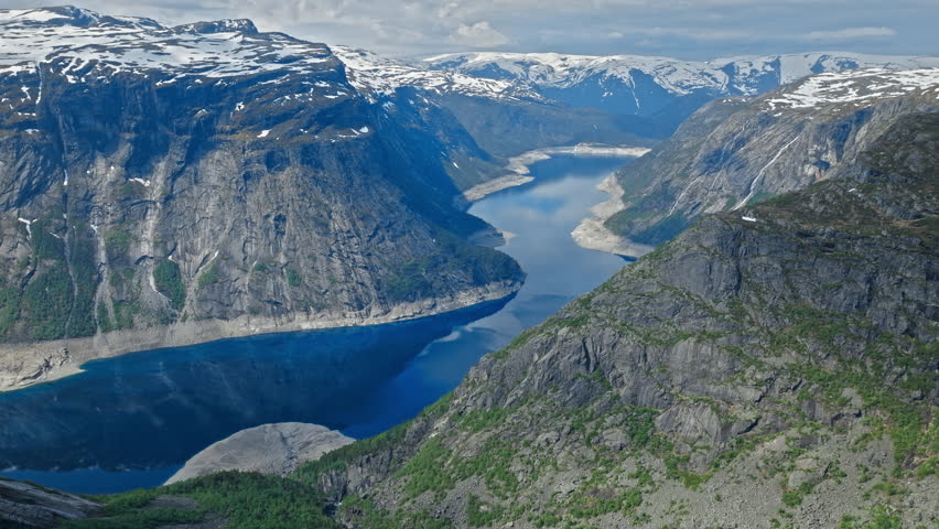Rocky ledge overlooking the fjord at Trolltunga in Norway. Cinematic view highlighting iconic cliff formations and vast Nordic mountain scenery on a sunny day.