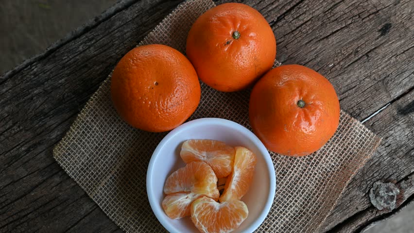several oranges fruit and slices in a white plate on an old wooden table