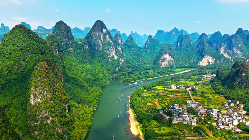 Aerial shot of spectacular karst mountain peaks and winding river with rural village scenery in Guilin, China. 
