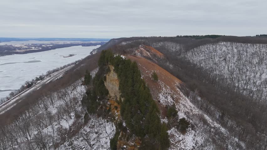 A high ridge in the Driftless Area reveals rolling bluffs, leafless forests, and frozen waterways surrounding Winona, Minnesota.