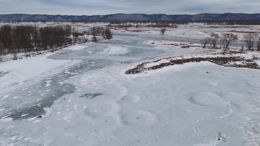 The Driftless winter landscape reveals braided, frozen waterways wrapping around small wooded islands and open snow-covered ground.