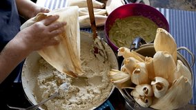 Unrecognizable woman spreading masa on a corn husk and adding chicken green chili filling - Powered by Shutterstock - Get 15% off with code: PIKWIZARD15