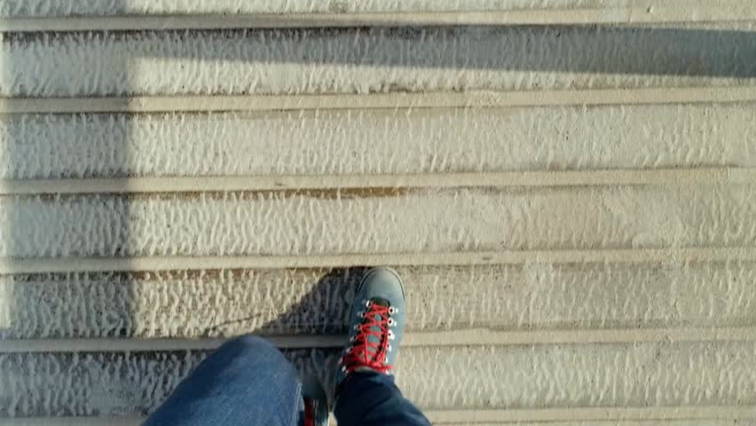 POV shot of man walking on empty boardwalk by the beach, blue boots with red laces, capturing movement, lifestyle, and reflection vibes.