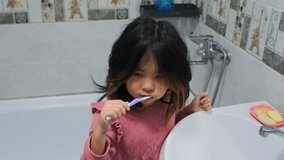 young girl cleaning teeth at sink in bathroom, asian girl actively brushing teeth during nightly bathroom routine, focused asian girl practicing oral hygiene at sink during evening routine in tiled - Powered by Shutterstock - Get 15% off with code: PIKWIZARD15