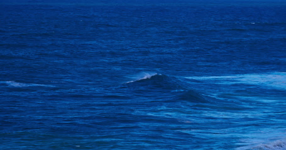 Deep Blue Ocean Waves with Foaming Crests Rolling Across the Vast Expanse of the Sea