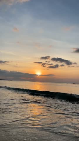 Golden Sunset Over Ocean with Waves Rolling on Sandy Beach Wide Shot Vertical