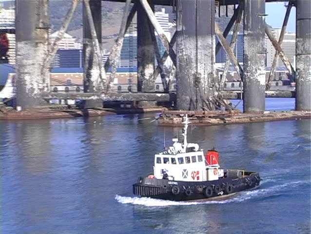Tug boat passes offshore drill rig