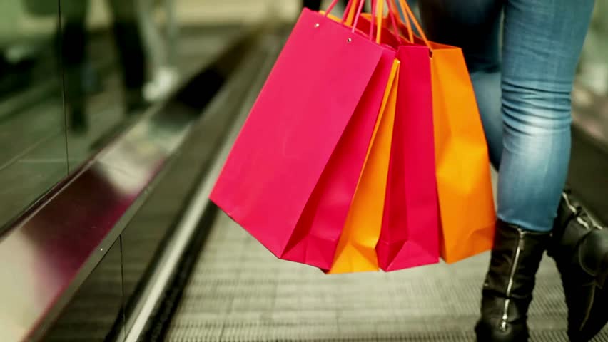 Unrecognizable shopaholic woman at escalator store boutique mall corridor shopping center concept 4k woman walks with shopping bag blurred stores