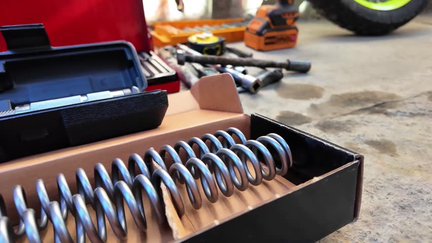 Close-up pan of motorcycle suspension with tools around in garage setting