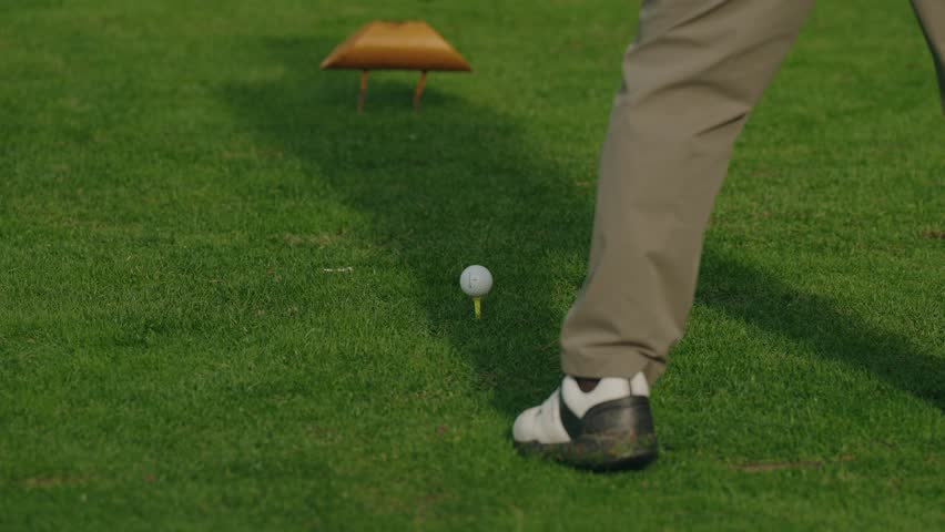 Close view of golfer hitting golf ball with driver on grass