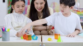 Smiling teacher helps two elementary students explore colorful geometric solids in bright classroom setting - Powered by Shutterstock - Get 15% off with code: PIKWIZARD15