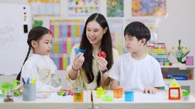Smiling teacher helps two elementary students explore colorful geometric shapes in bright classroom - Powered by Shutterstock - Get 15% off with code: PIKWIZARD15