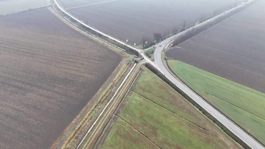 Aerial view of a rural crossroads with fields and a highway in the distance