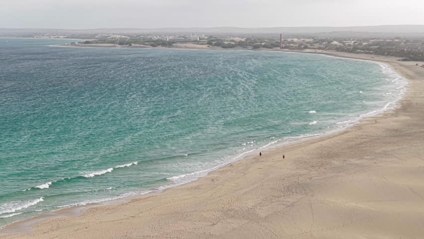Nice drone view of two people walking on sandy beach in Boa Vista island, Cape Verde.