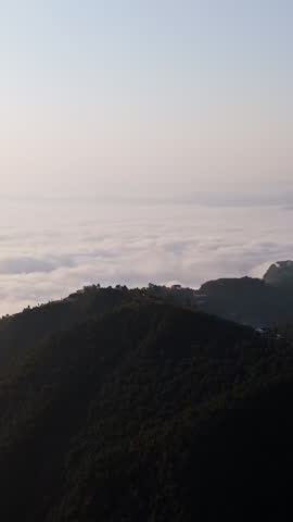 Vertical drone shot overlooking Gyarjati town and foggy lake Phewa, sunrise in Nepal