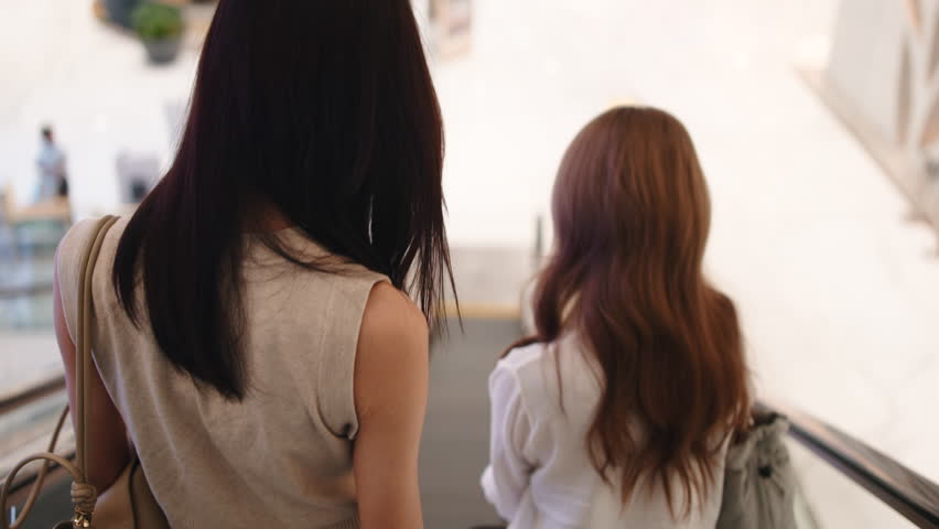 Two women going down escalator in a shopping mall