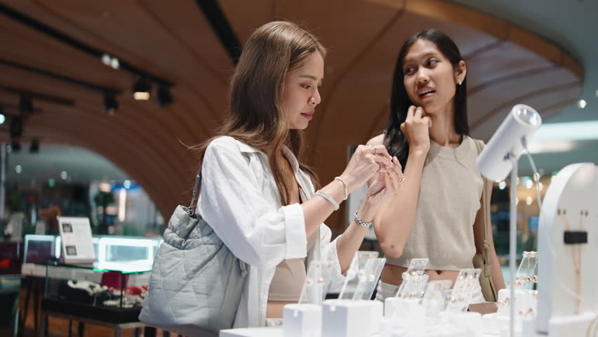 Happy female friends choosing jewelry in store