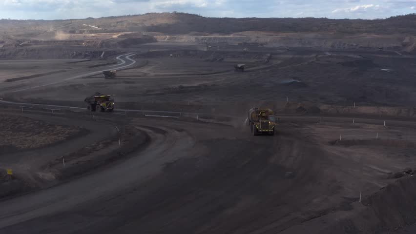 Aerial view of a massive truck traversing through the stark, dark landscape of a mine, contrasting with the pale sky, Tete, Tete Province, Mozambique.