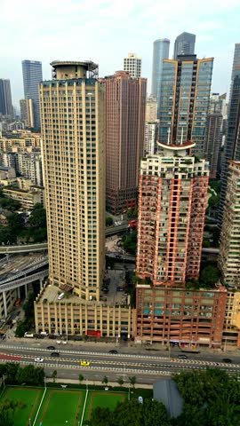 Aerial view of skyscrapers casting long shadows over roads and greenery, creating a stark contrast between urban density and nature, Chongqing, Chongqing, China.