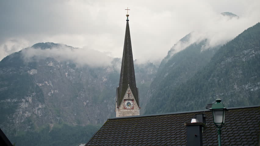 Traditional church architecture in Hallstatt Austria. Cathedral with clock on tower in urban landscape of Alpine village.