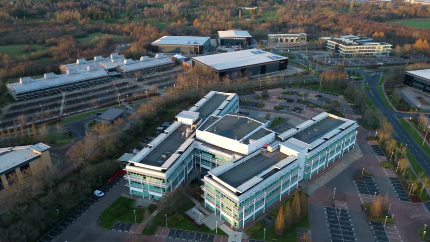 Aerial view of modern buildings with surrounding car parks and roads, creating a contrasting blend of urban infrastructure and natural landscapes, Solihull, England, United Kingdom.
