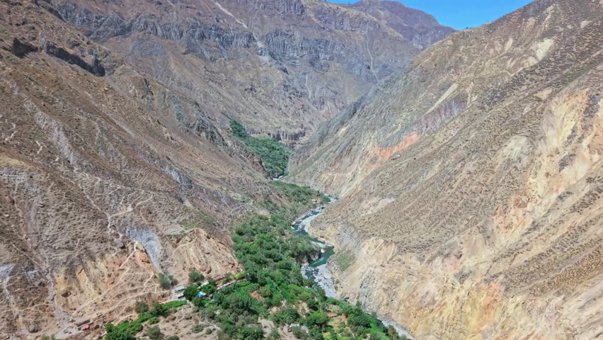 From above, the green trees fed by the Río Colca appear like a giant living snake winding through a crack in the earth. The immense Colca Canyon frames this powerful contrast of life and barren stone