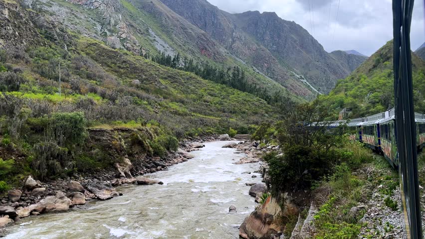Peru Rail train Inca Trail Ollantaytambo in route Aguas Clients Amazon Urubamba river Machu Picchu temple Peruvian Andes mountains range peaks rainy season sunny blue sky clouds forward motion