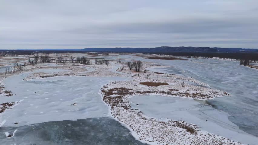 Wetland ecosystem during winter, dry trees and frozen lazy river covered in snow many islands Wisconsin Minnesota Driftless Region