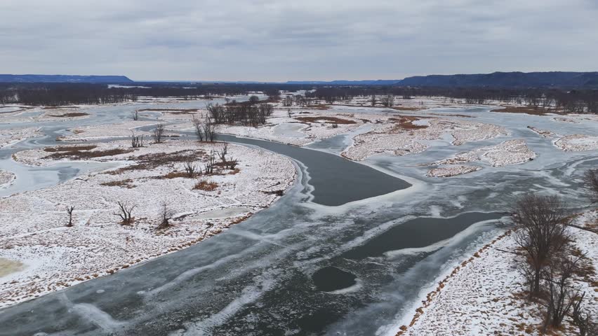 Winter silence surrounds a frozen waterway where overlapping ice slabs create dramatic natural patterns. Driftless, Wisconsin Minnesota boarder