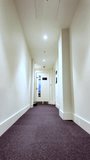 Office corridor with white walls and dark carpet leading to a door, creating a strong vanishing point. vertical video - Powered by Shutterstock - Get 15% off with code: PIKWIZARD15
