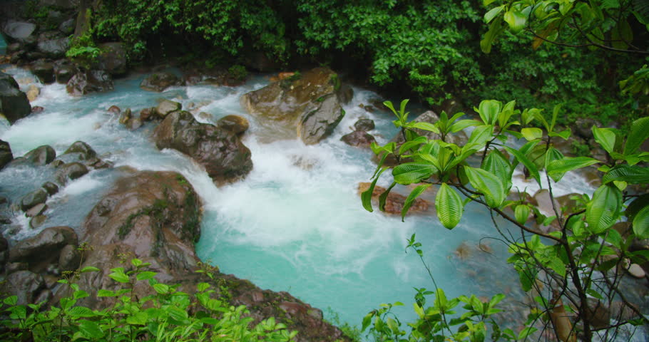 Turquoise river rapids flowing in lush rainforest of Costa Rica during rainy weather