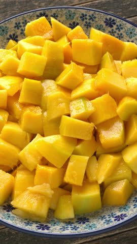 A rotating platter with ripe mango chunks on rustic boards. Vertical video.