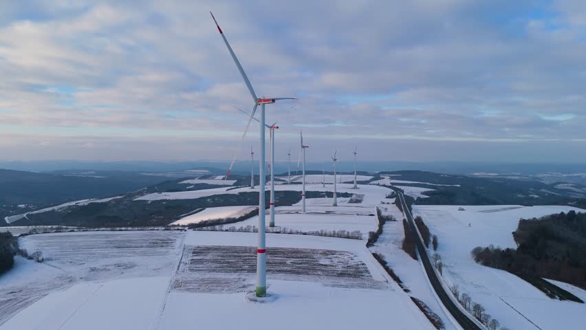 Windless wind turbine in snow, dark doldrums or wind lull in winter, renewable sustainable energy, environmental conversation, Germany