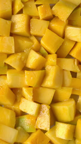 Rotation of ripe mango chunks. Background texture. Vertical video.