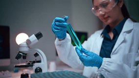 Young Asian female scientist wearing protective gear analyzing a chemical sample in a test tube. Clinical research in a modern laboratory - Powered by Shutterstock - Get 15% off with code: PIKWIZARD15