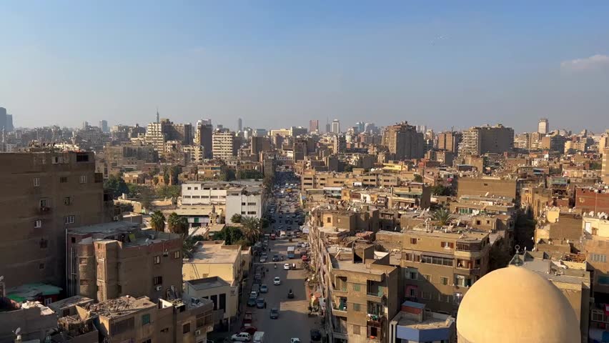 Aerial panoramic view of Cairo cityscape with apartment buildings, calm suburban streets, and cars driving, capturing Egypt’s capital urban life.