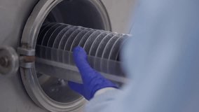 Cleanroom technician loading a silicon wafer cassette into a vacuum processing chamber with protective gloves, ensuring precision handling in a controlled environment. - Powered by Shutterstock - Get 15% off with code: PIKWIZARD15