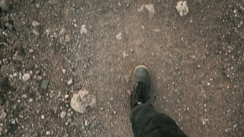POV of a man walking on a gravel trail in hiking boots, enjoying the outdoor adventure, camping, and slow-motion journey in nature.