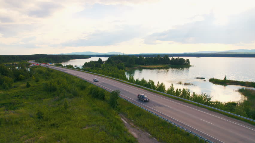 Aerial view of cars driving along a scenic lakeside road