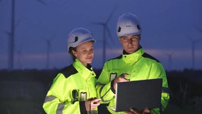 Engineers wearing safety helmets and jackets inspecting a wind turbine at wind farm at dusk. Concept renewable energy, sustainable technology wind power maintenance and environmental engineering. - Powered by Shutterstock - Get 15% off with code: PIKWIZARD15